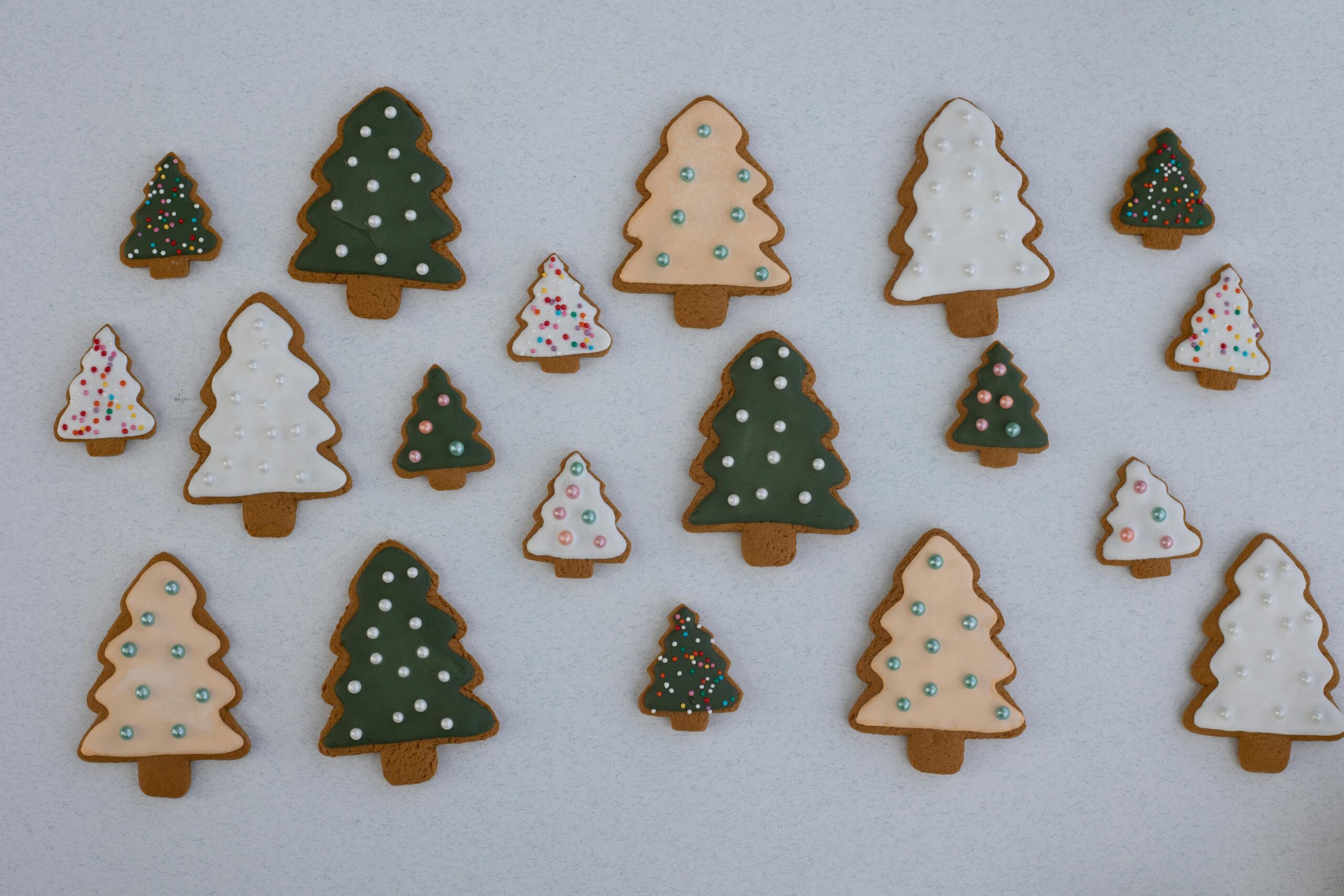 Different sizes of christmas tree shaped gingerbread cookies on white background